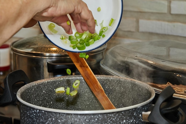 Chef throws leek into pot on gas stove