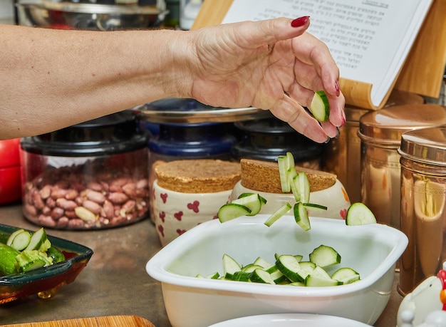 Chef throws sliced zucchini into the bowl to prepare the dish