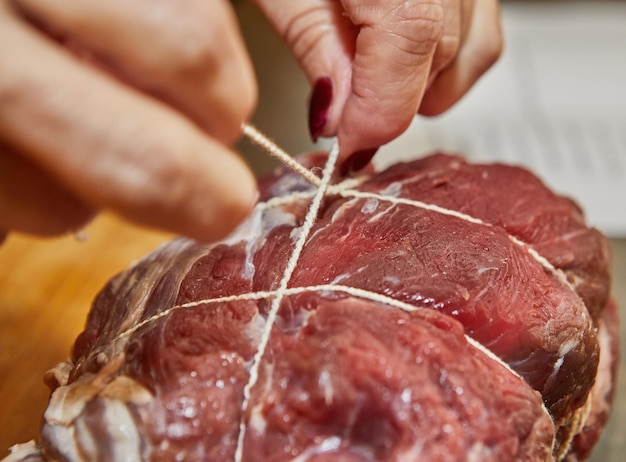 Chef ties the beef with rope and prepares it for baking in the oven