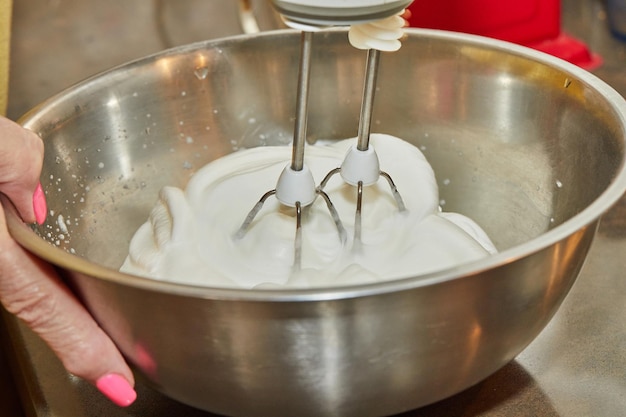 Chef whips egg whites with mixer in bowl