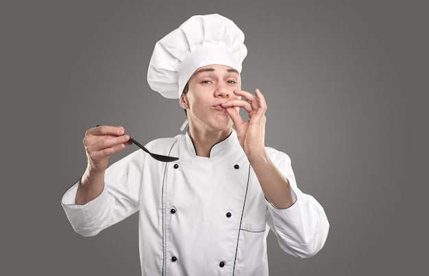 Chef with spoon tasting exquisite dish