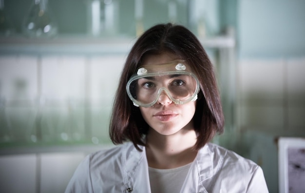 Chemical laboratory young woman in work glasses looking in the camera