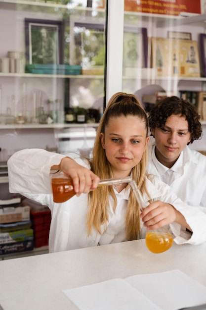 Chemistry lesson Schoolgirl and classmates holds flask for experiments and smiles in the laboratory School education