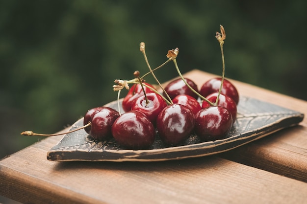 cherries on a ceramic plate in the shape of a leaf