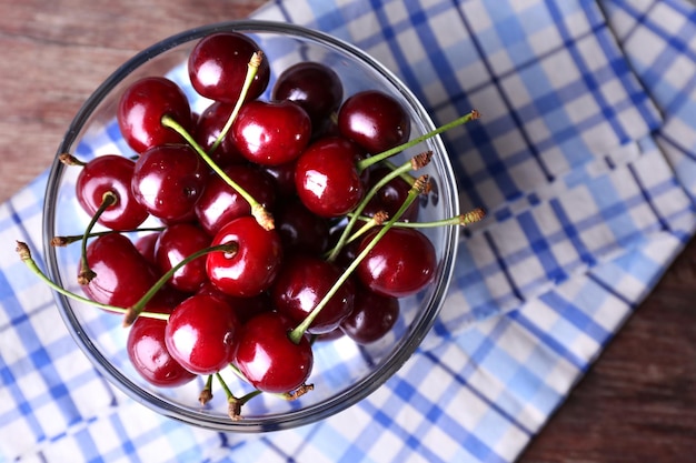 Cherries in color bowl on wooden background