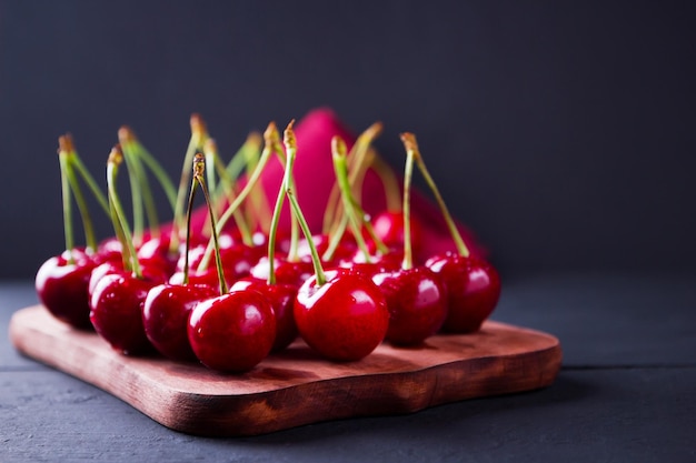 Cherries on dark background Red cherries on wooden board Berries in drops of water on red napkin