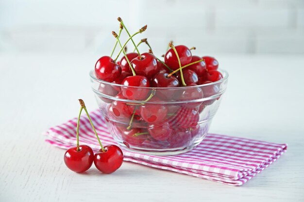 Cherries in glass bowl on table on light background