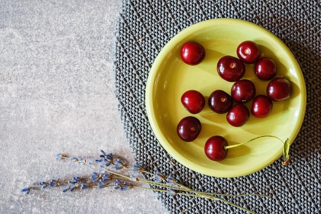 Cherries in a green plate on a gray marble table