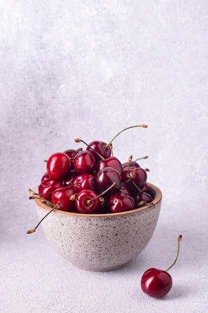 Cherries in round beige cup on background of gray plaster