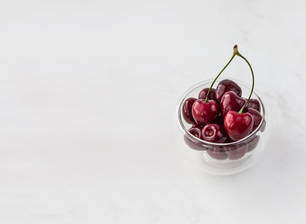 Cherries in a transparent bowl on a white background with space for text Vitamins and a healthy lifestyle