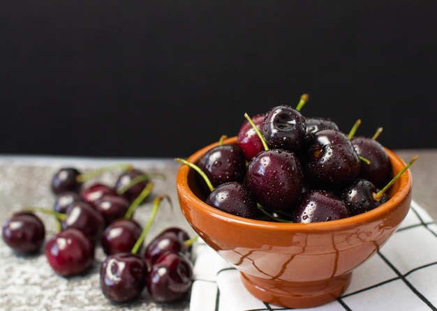 Cherries with drops in a bowl on a black background