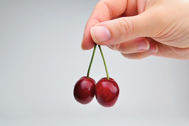 Cherries in the womens hand isolated on white background Two ripe cherries in a woman hand isolated on a white background The hand with the berries