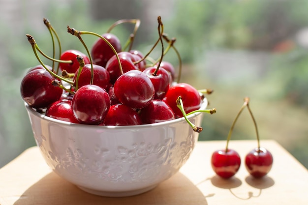 Cherry berries in a white bowl under the sun