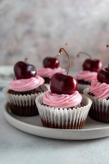 Cherry chocolate cupcakes with pink cream Homemade baked treat or dessert