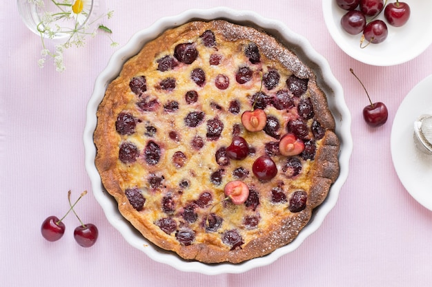 Cherry clafoutis in baking dish on pink table