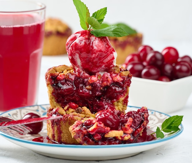 Cherry crumble pie decorated with a scoop of ice cream and drizzled with cherry sauce