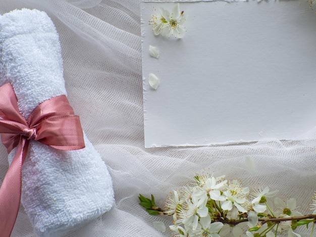 Cherry flowers towel with pink bow and paper card with copy space