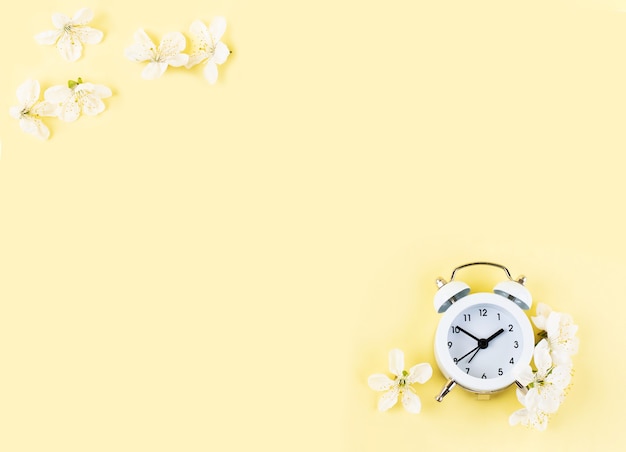 Cherry flowers and vintage alarm clock on yellow