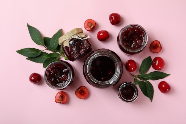 Cherry jam and ingredients on pink background