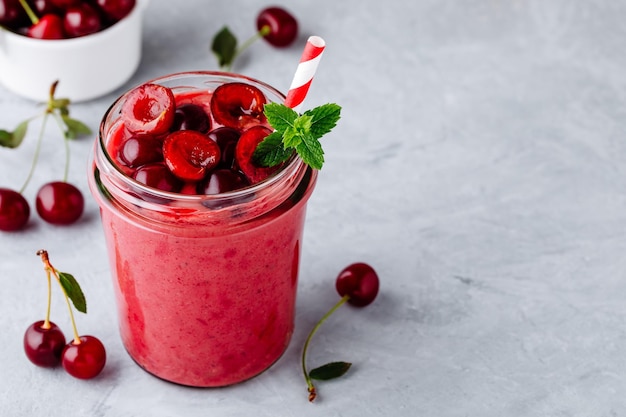 Cherry smoothie in glass jars with mint leaves and fresh berries