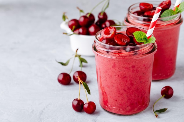 Cherry smoothie in glass jars with mint leaves and fresh berries