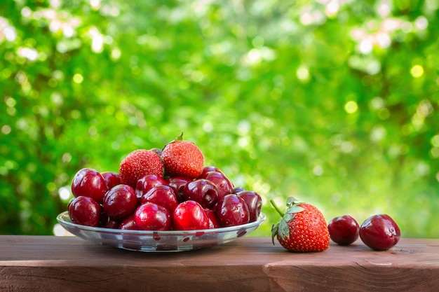 Cherry and Strawberry on a glass platter. Bright sunny day. Juicy, tasty, healthy fruits.