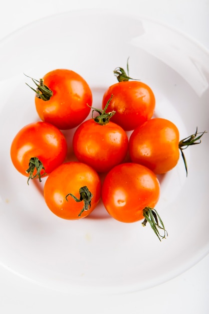 cherry tomatoes for adding to pizza on a white plate