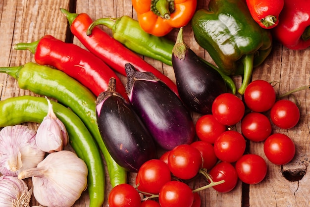 Cherry tomatoes, peppers, garlic, eggplants on a wooden table. Fresh organic vegetables.