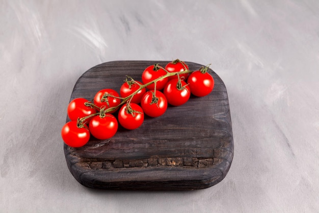 Cherry tomatoes on wooden board Grey background selective focus