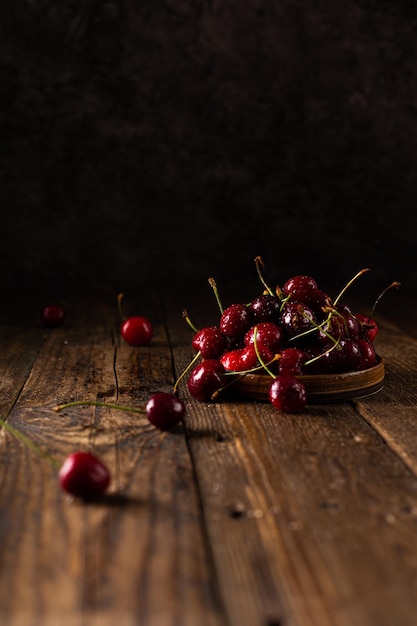 Cherry with water drops on a dark brown wooden table Rustic style