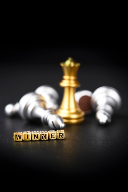 A chess board game. The winning business concept: competition and management. A golden chess piece on a dark background. Word winner. Copy space for text.