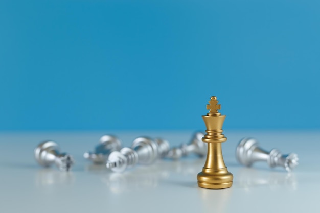 Chess game gold king standing confront the silver team blue background business leader strategy concept