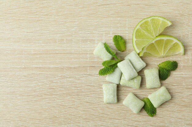 Chewing gum with lime and mint on wooden background