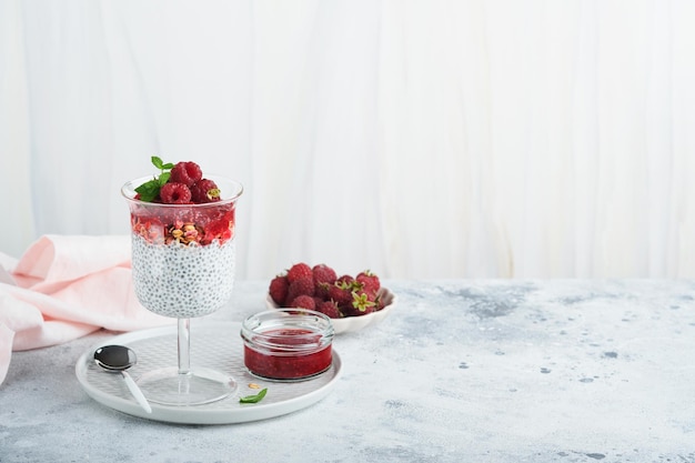 Chia pudding Healthy vanilla chia pudding in glass with fresh raspberries and mint on white background Vegan healthy breakfast