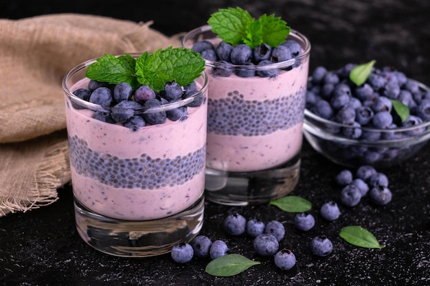 Chia pudding with blueberries in a glass on a black background.