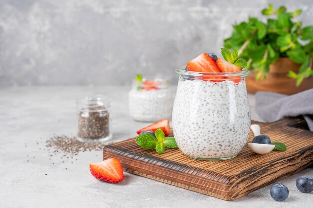 Chia pudding with fresh strawberry and blueberry on top in a glass jar Healthy breakfast