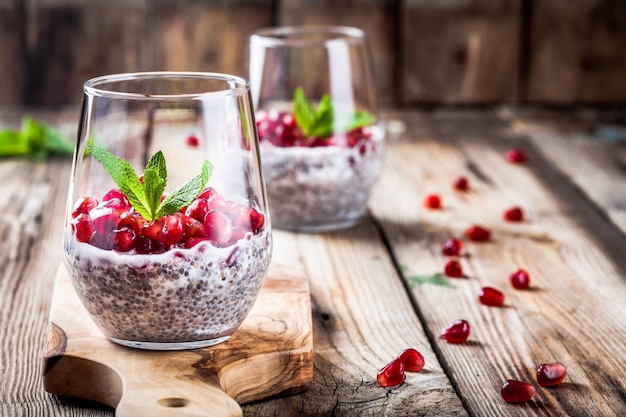 Chia pudding with pomegranate seeds and mint on rustic wooden table