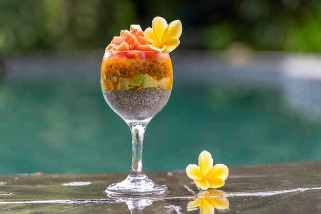 Chia seeds pudding with papaya passion fruit mango and avocado in a glass for breakfast on the background of the swimming pool water closeup The concept of healthy eating superfood