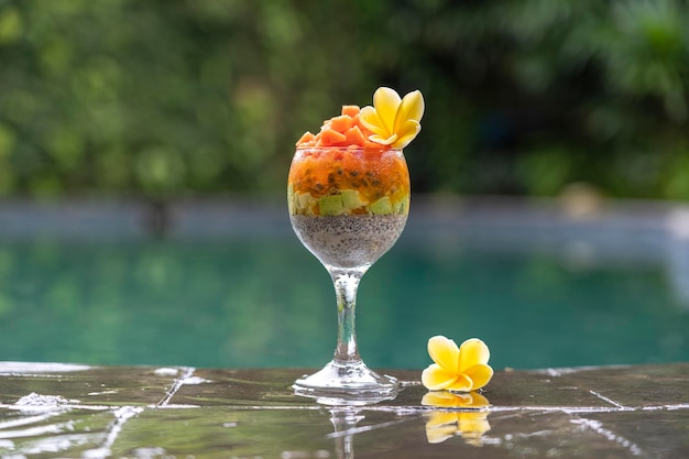 Chia seeds pudding with papaya passion fruit mango and avocado in a glass for breakfast on the background of the swimming pool water closeup The concept of healthy eating superfood