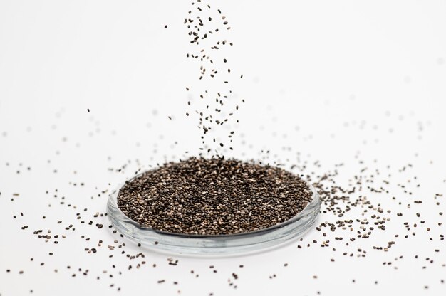 Chia seeds on a white surface in a glass bowl