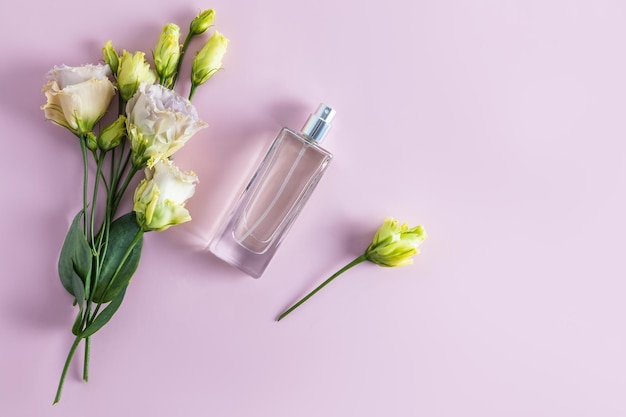 A chic bottle of women's perfume and a delicate bouquet of Austoma flowers on a pastel background Top view A copy of the space Layout of the product