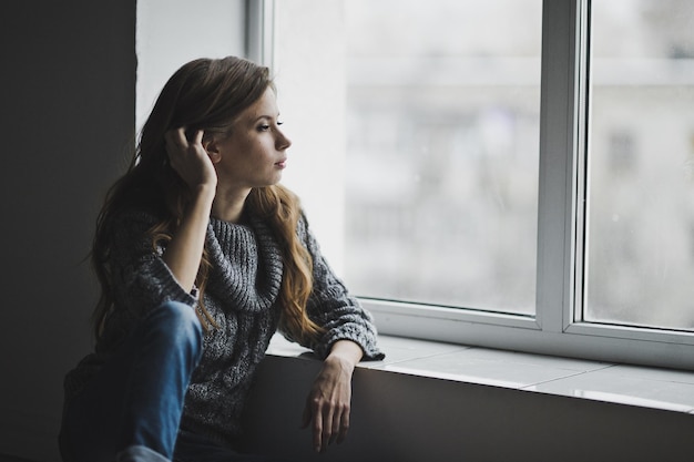 Chic girl thoughtfully looks into a large bright window 6999