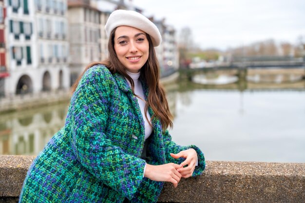 Photo chic woman smiling at camera leaning next to the river