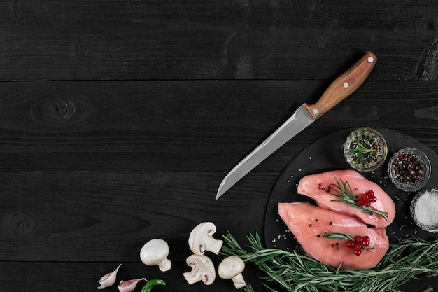 Chicken breast on a cutting board with herbs and different vegetables on rustic wooden background Top view Copy space Still life Flat lay