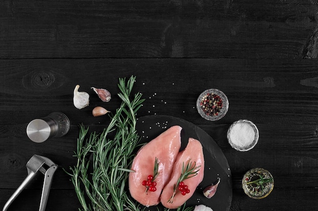 Chicken breast on a cutting board with herbs spices and garlic press on rustic wooden background Top view Copy space Still life Flat lay