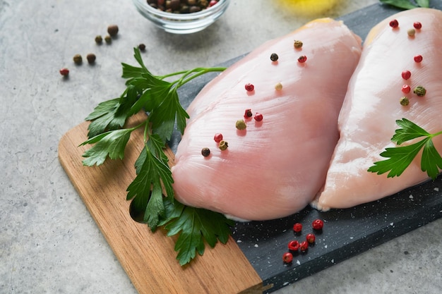 Chicken breast Two Chicken fillet with spices olive oil and parsley on black stone cutting board on grey stone table background Top view with copy space Food meat cooking background