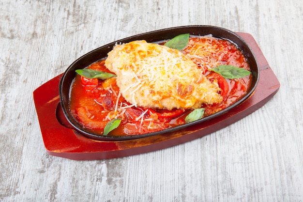 chicken breast with cheese with stewed tomatoes in a pan