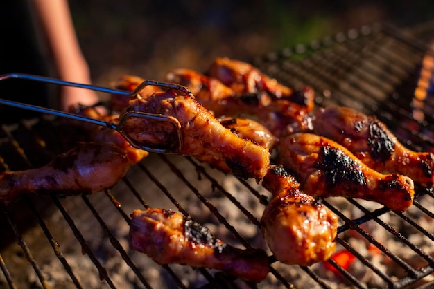 Chicken drumsticks are grilled on a barbecue grill in the evening