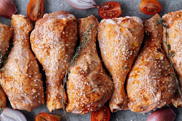 Chicken drumsticks with spices paprika and sesame seeds ready to bake on a baking sheet