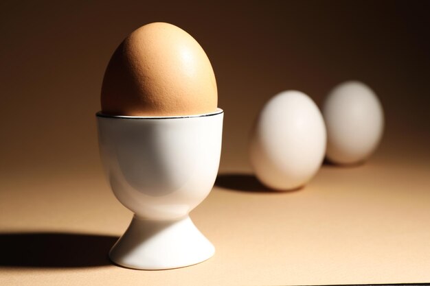 Chicken egg in cup on beige background Space for text